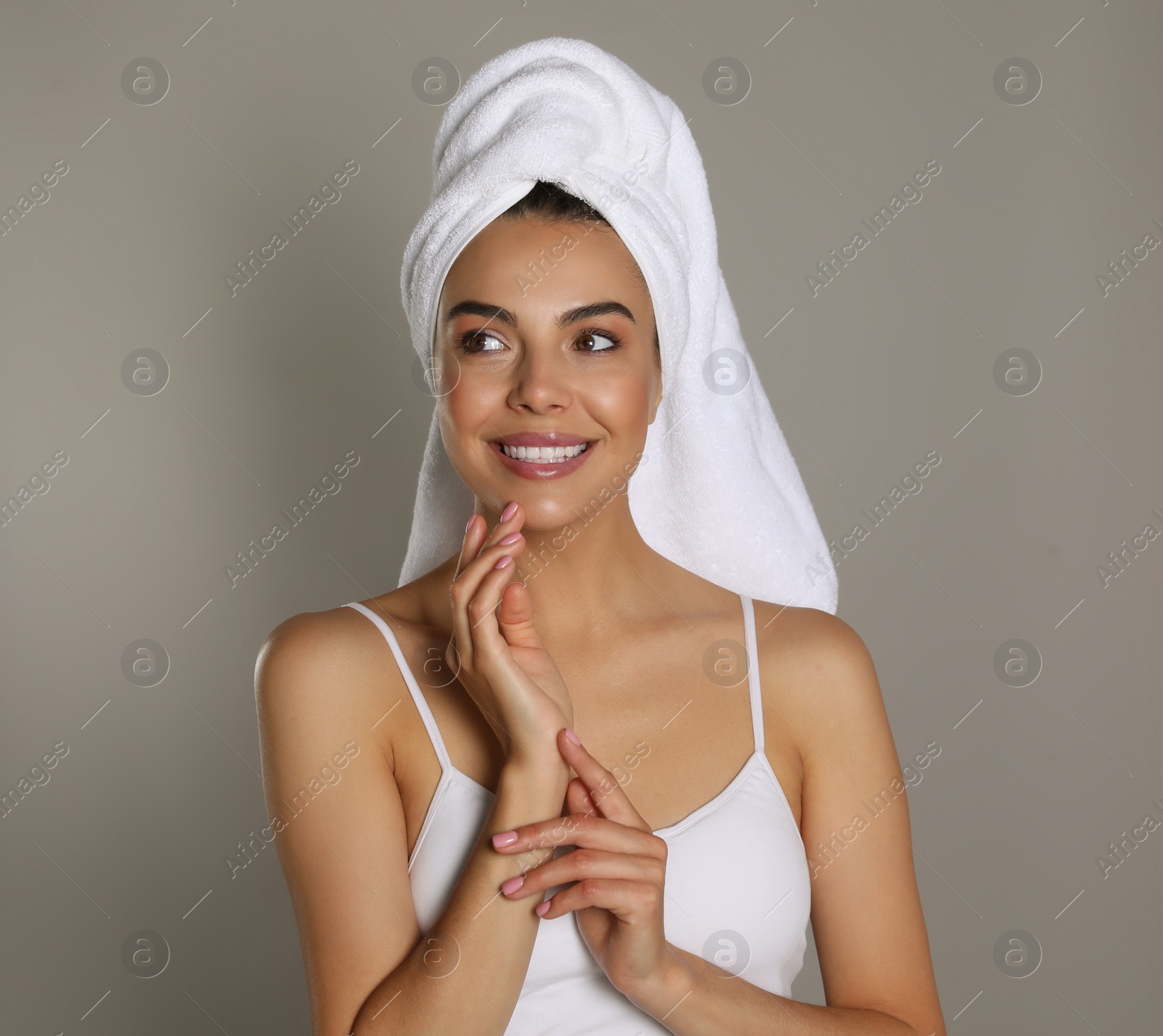 Photo of Beautiful young woman with towel on head against grey background