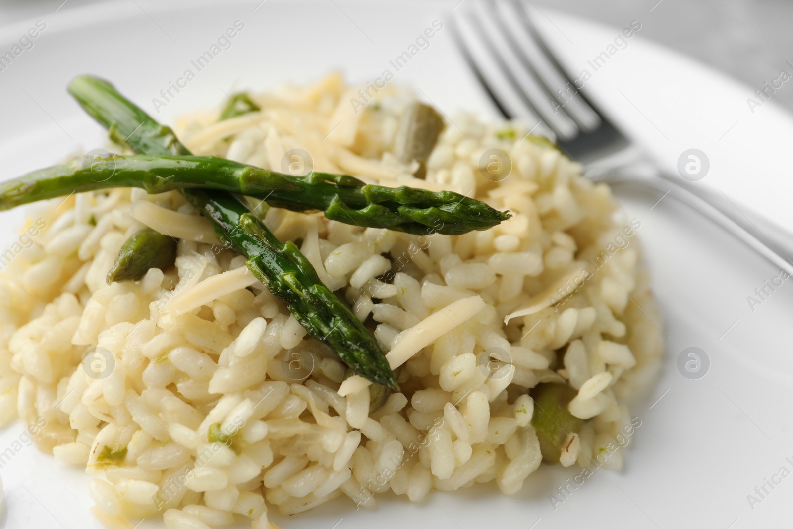 Photo of Delicious risotto with asparagus in plate, closeup