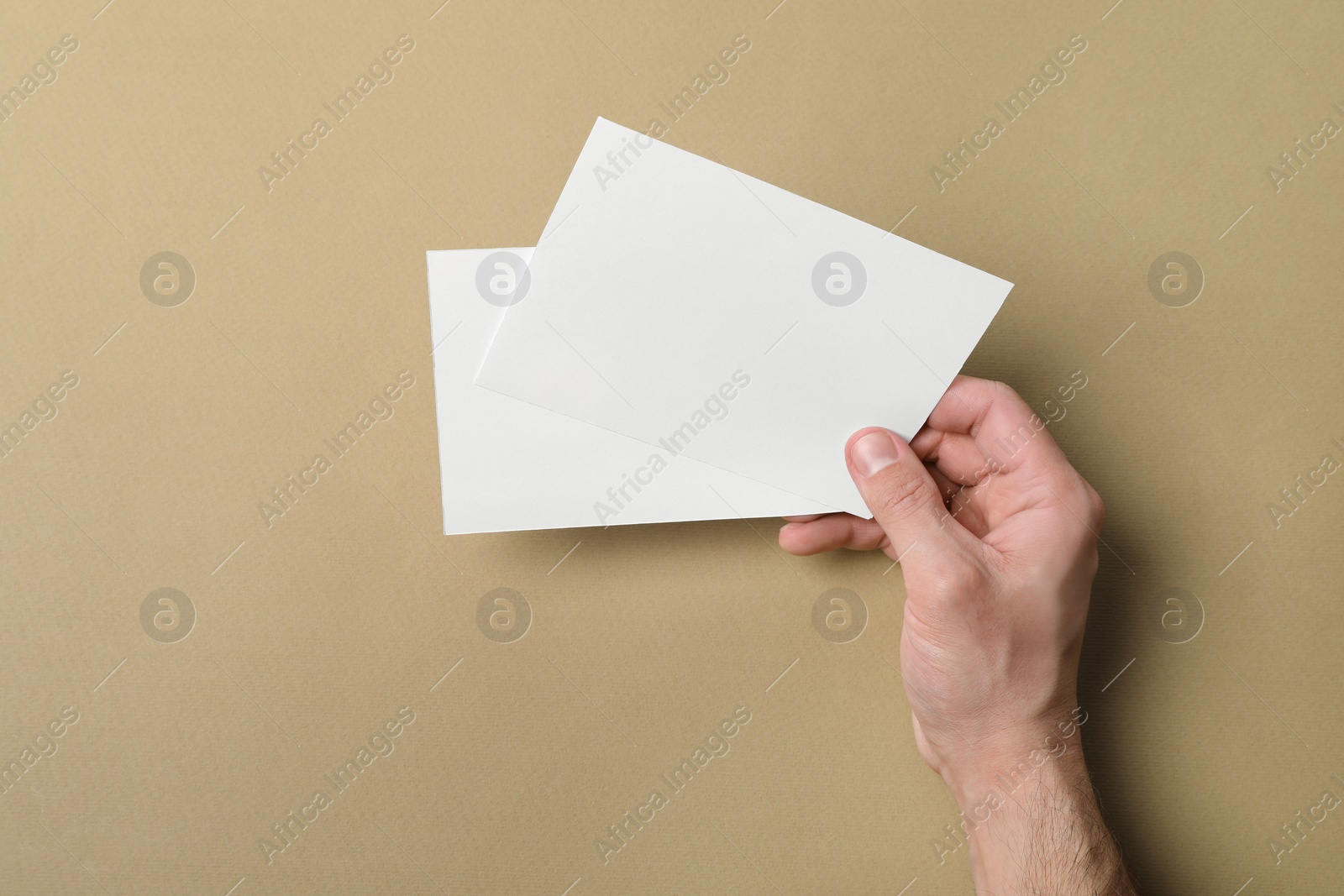 Photo of Man holding flyers on light brown background, closeup. Mockup for design