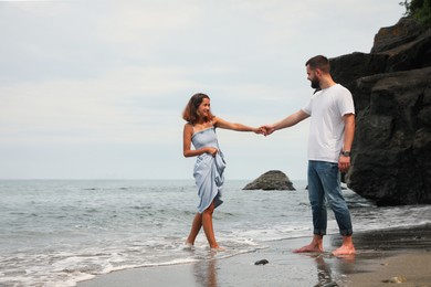 Photo of Happy young couple spending time together on beach near sea. Space for text