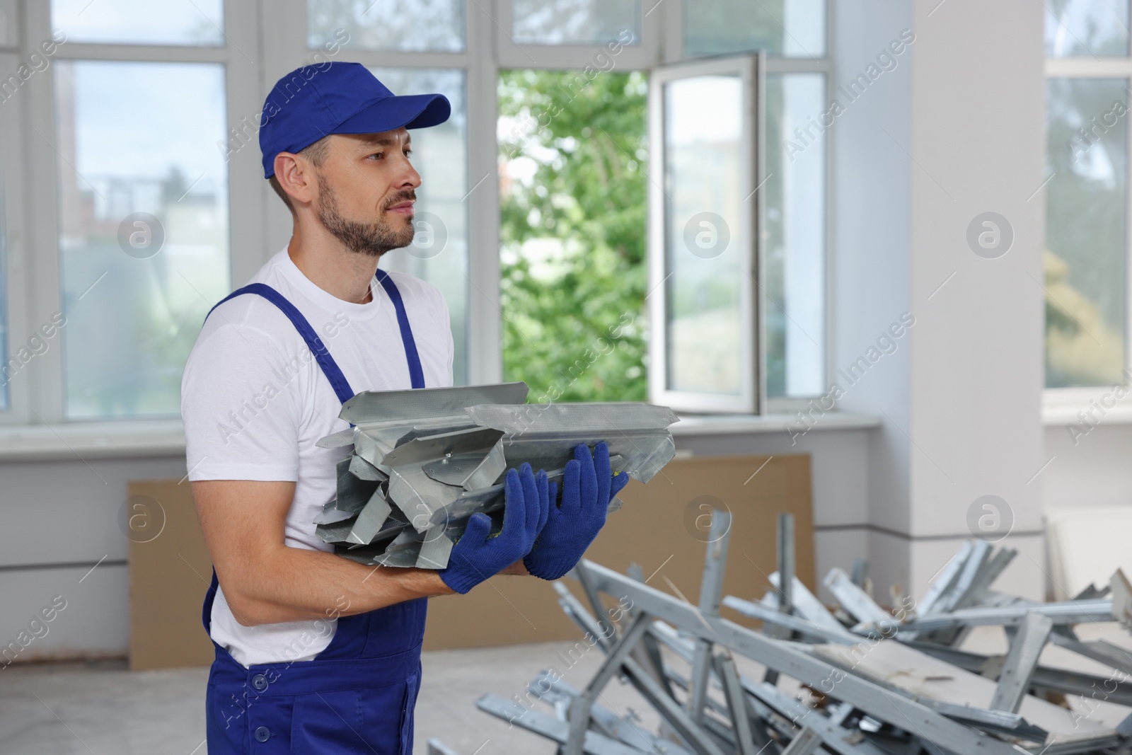 Photo of Construction worker holding used building materials in room prepared for renovation