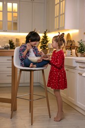 Photo of Cute little children making dough for Christmas cookies in kitchen