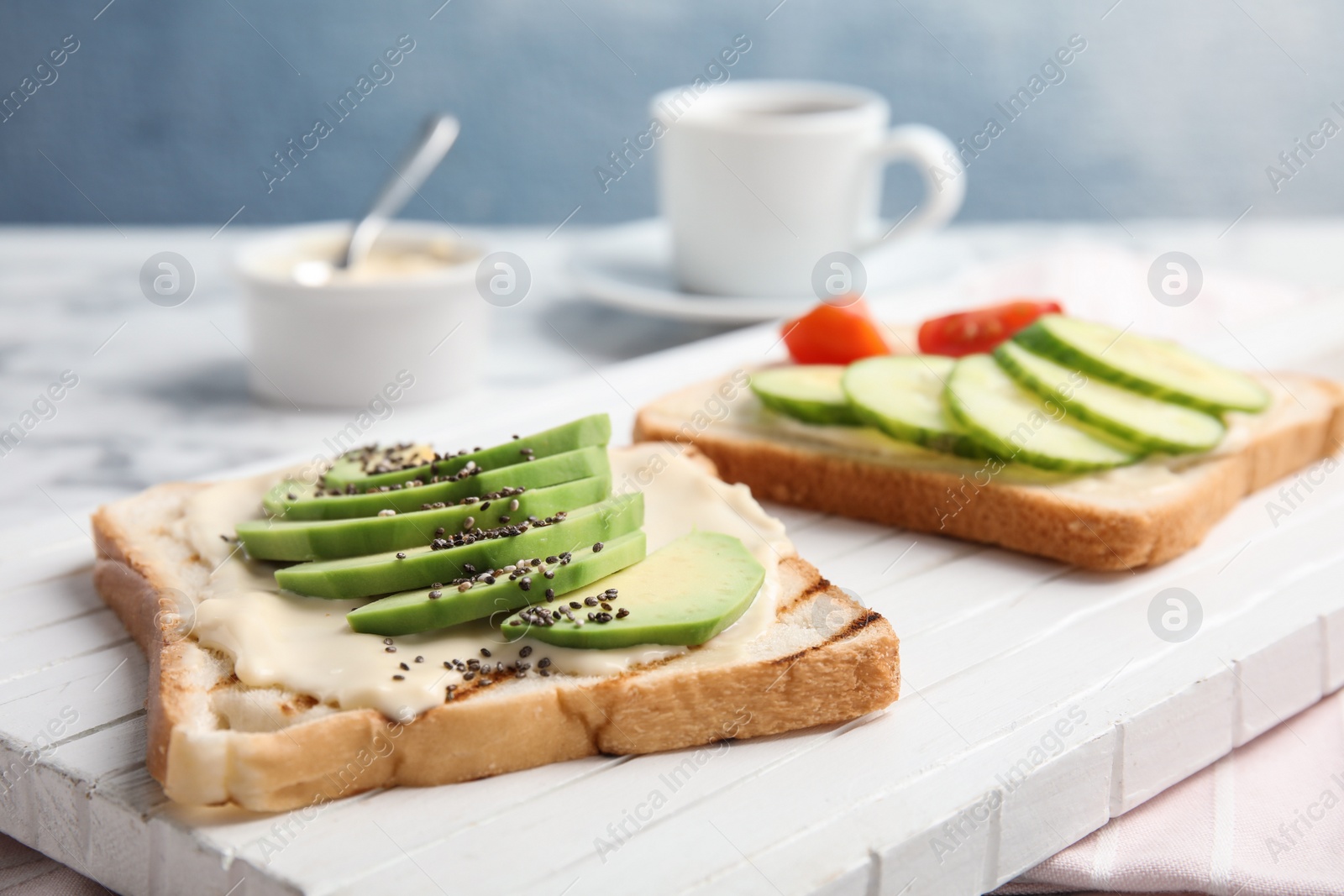 Photo of Slices of bread with different toppings on white wooden board