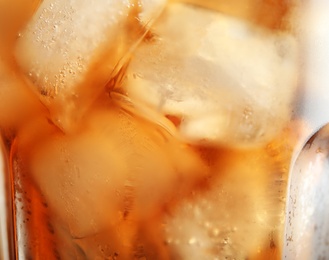 Photo of Glass of tasty refreshing cola with ice cubes, closeup