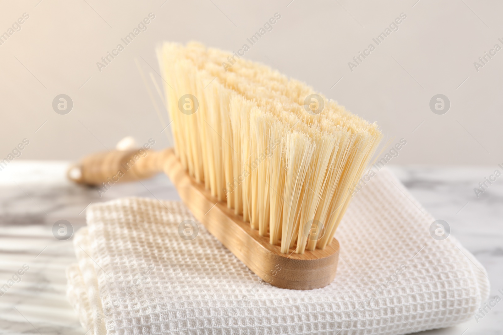 Photo of One cleaning brush and rag on white marble table, closeup