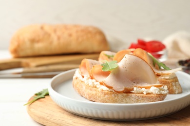 Board with plate of delicious chicken bruschettas on table