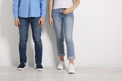 Photo of People in stylish jeans near white wall indoors, closeup