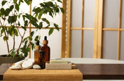 Photo of Wooden tray with spa products and stones on bath tub in bathroom. Space for text