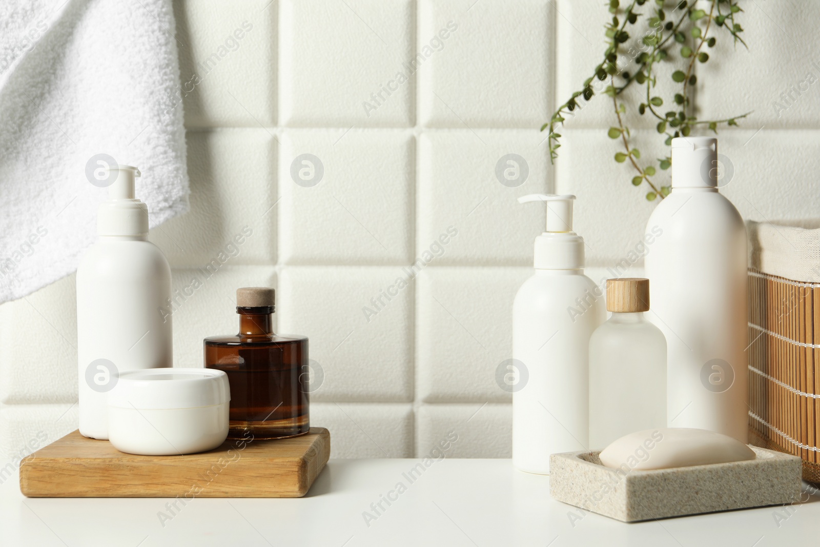 Photo of Different bath accessories and personal care products on white table near tiled wall