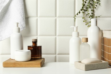 Photo of Different bath accessories and personal care products on white table near tiled wall