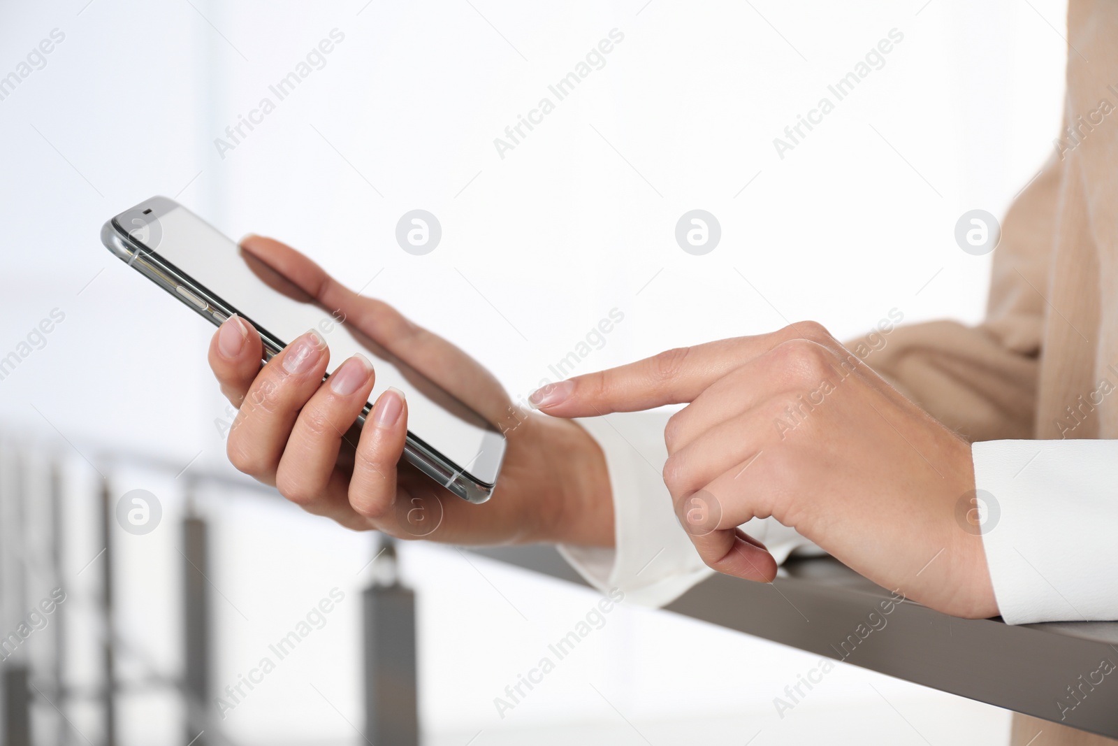 Photo of Young woman using modern smartphone indoors, closeup