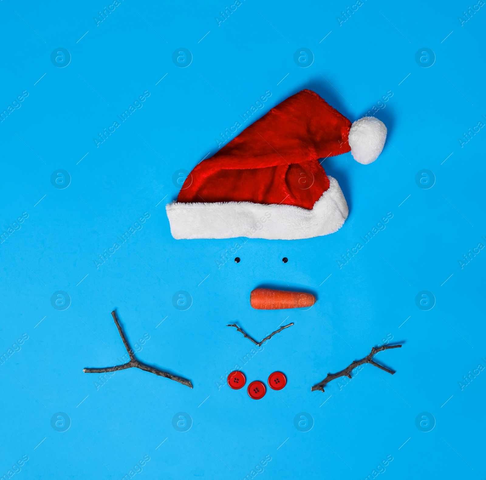 Photo of Creative snowman shape made of Santa hat and different items on light blue background, flat lay