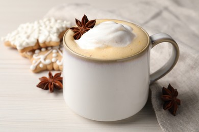 Cup of delicious eggnog with anise stars on wooden table, closeup