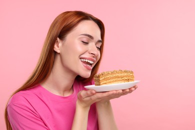 Photo of Young woman with piece of tasty cake on pink background, space for text