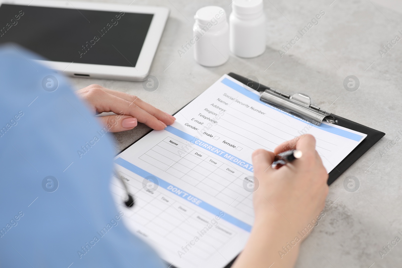 Photo of Doctor filling patient's medical card at table in clinic, closeup