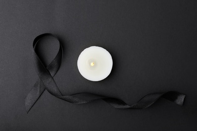 Photo of Ribbon and candle on black background, top view. Funeral symbols