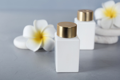 Photo of Cosmetic products, spa stones and tropical flowers on light grey table