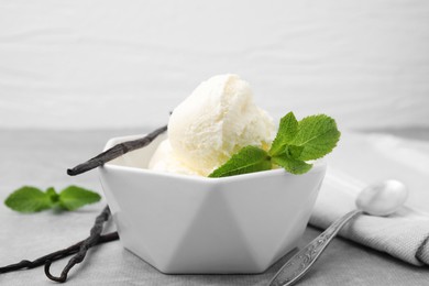 Photo of Delicious ice cream, mint, vanilla pods and spoon on light grey table, closeup