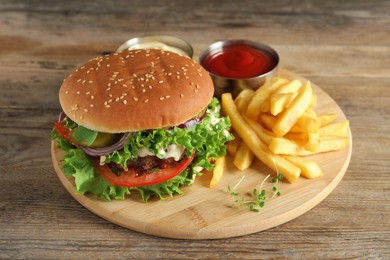Delicious burger with beef patty, tomato sauce and french fries on wooden table