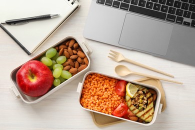 Photo of Healthy products high in vegetable fats near laptop on light wooden table, flat lay