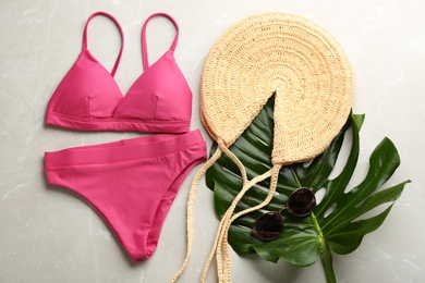 Photo of Beautiful pink bikini and beach accessories on light marble background, flat lay