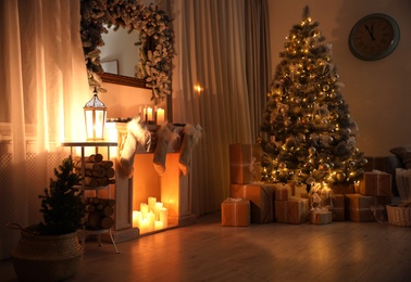 Photo of Stylish interior with decorative fireplace and beautiful Christmas tree in evening