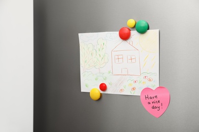 Photo of Kid's drawing and magnets on refrigerator door