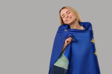 Photo of Happy woman with flag of European Union on grey background, space for text