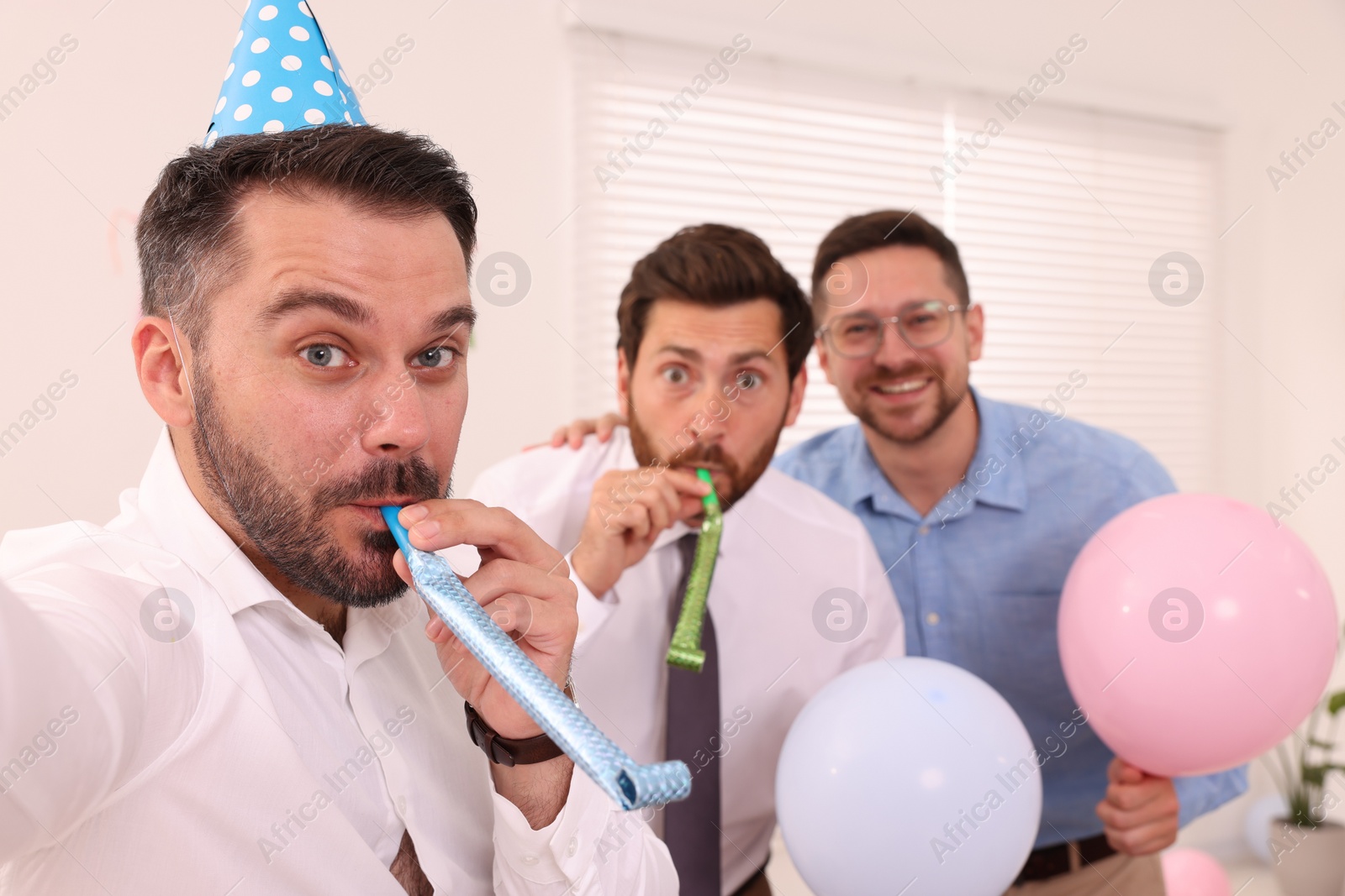 Photo of Coworkers taking selfie during office party indoors