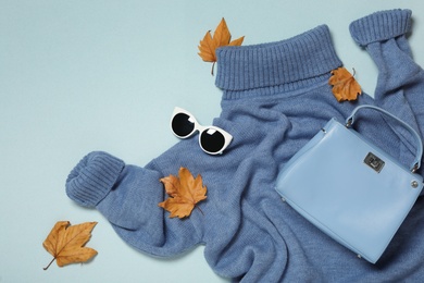 Photo of Flat lay composition with sweater and dry leaves on light blue background. Autumn season