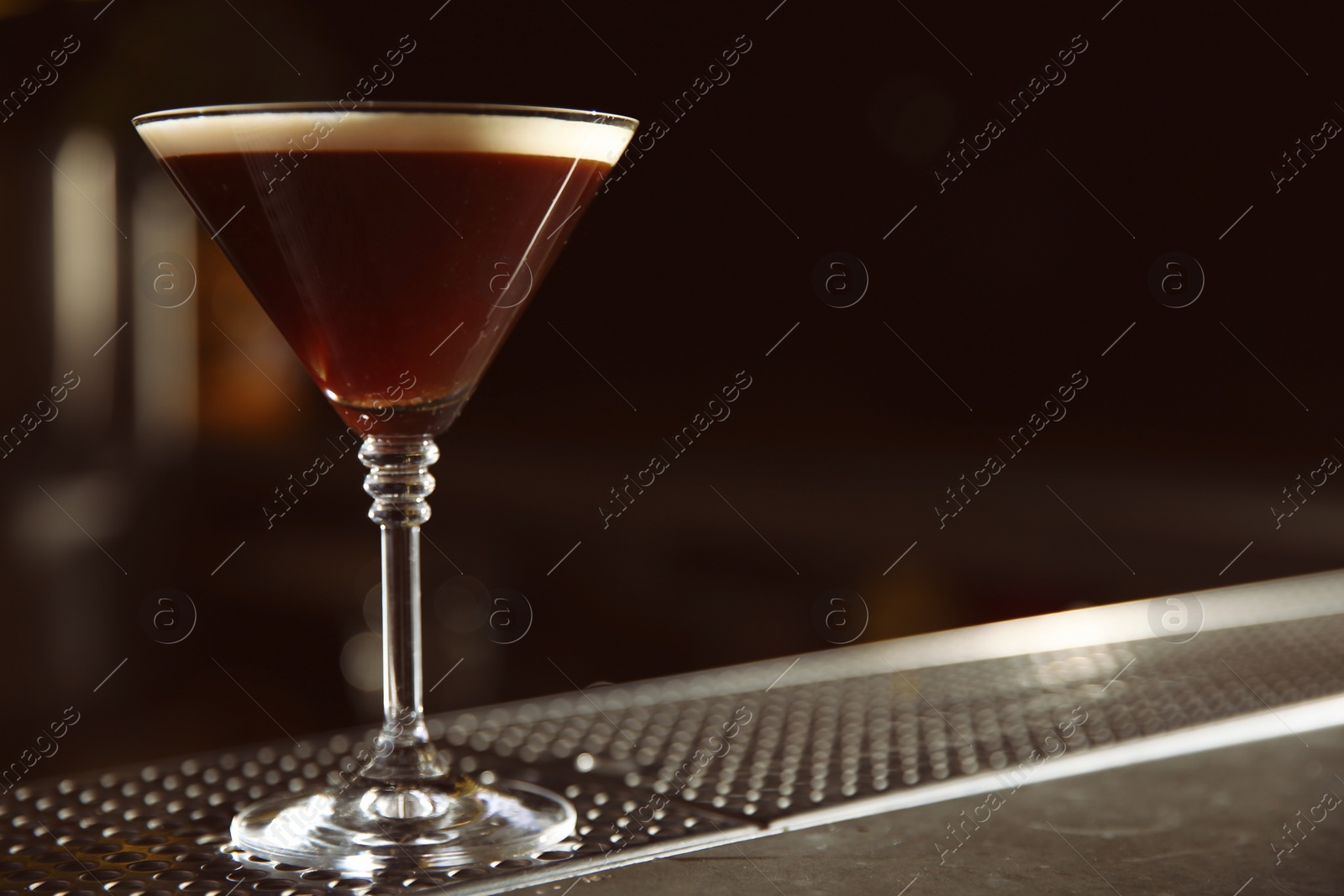 Photo of Glass of martini espresso cocktail on bar counter. Space for text