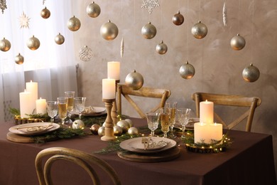 Photo of Christmas table setting with burning candles and festive decor