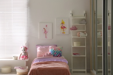 Photo of Bed with beautiful linens in children's room. Modern interior design