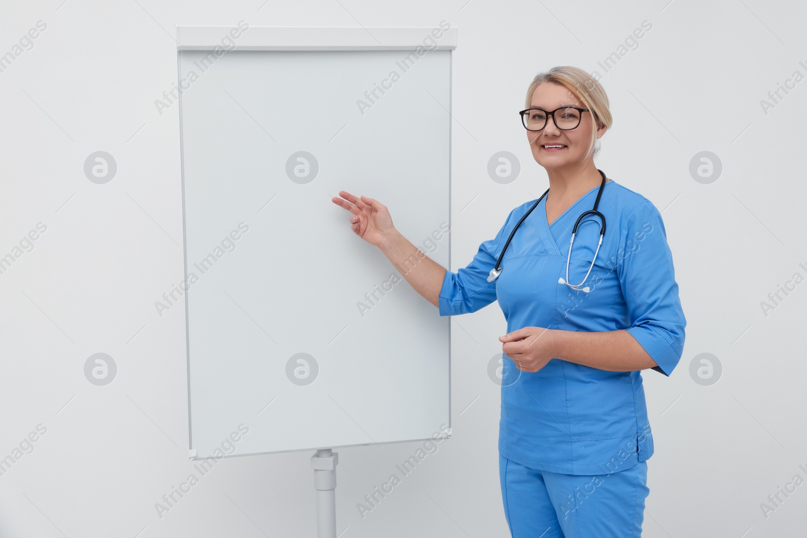 Photo of Professional doctor explaining something near flipchart indoors