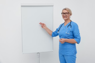 Professional doctor explaining something near flipchart indoors