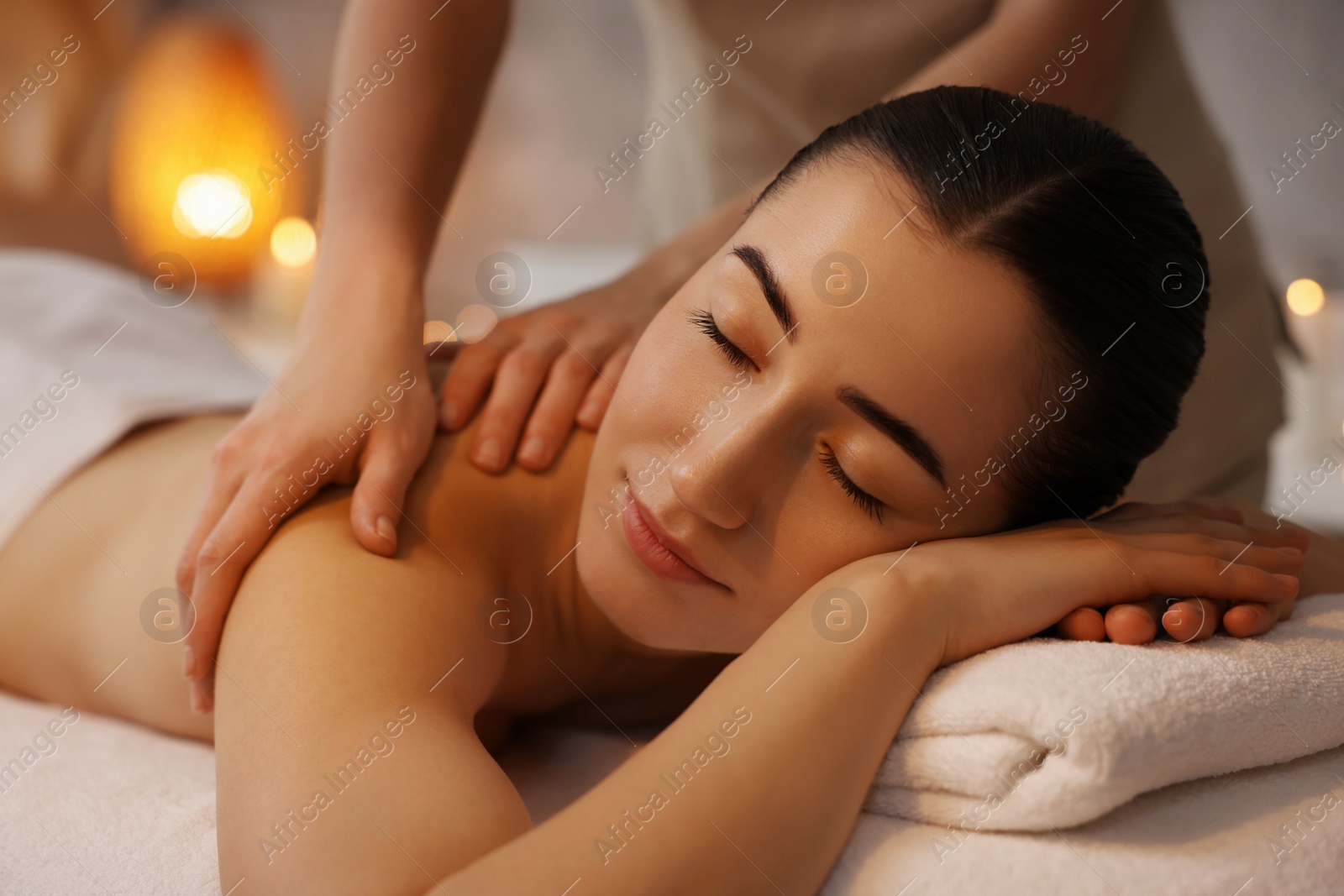 Photo of Woman receiving back massage on couch in spa salon