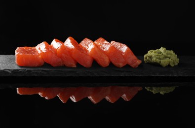 Photo of Delicious salmon sashimi and wasabi on black mirror surface