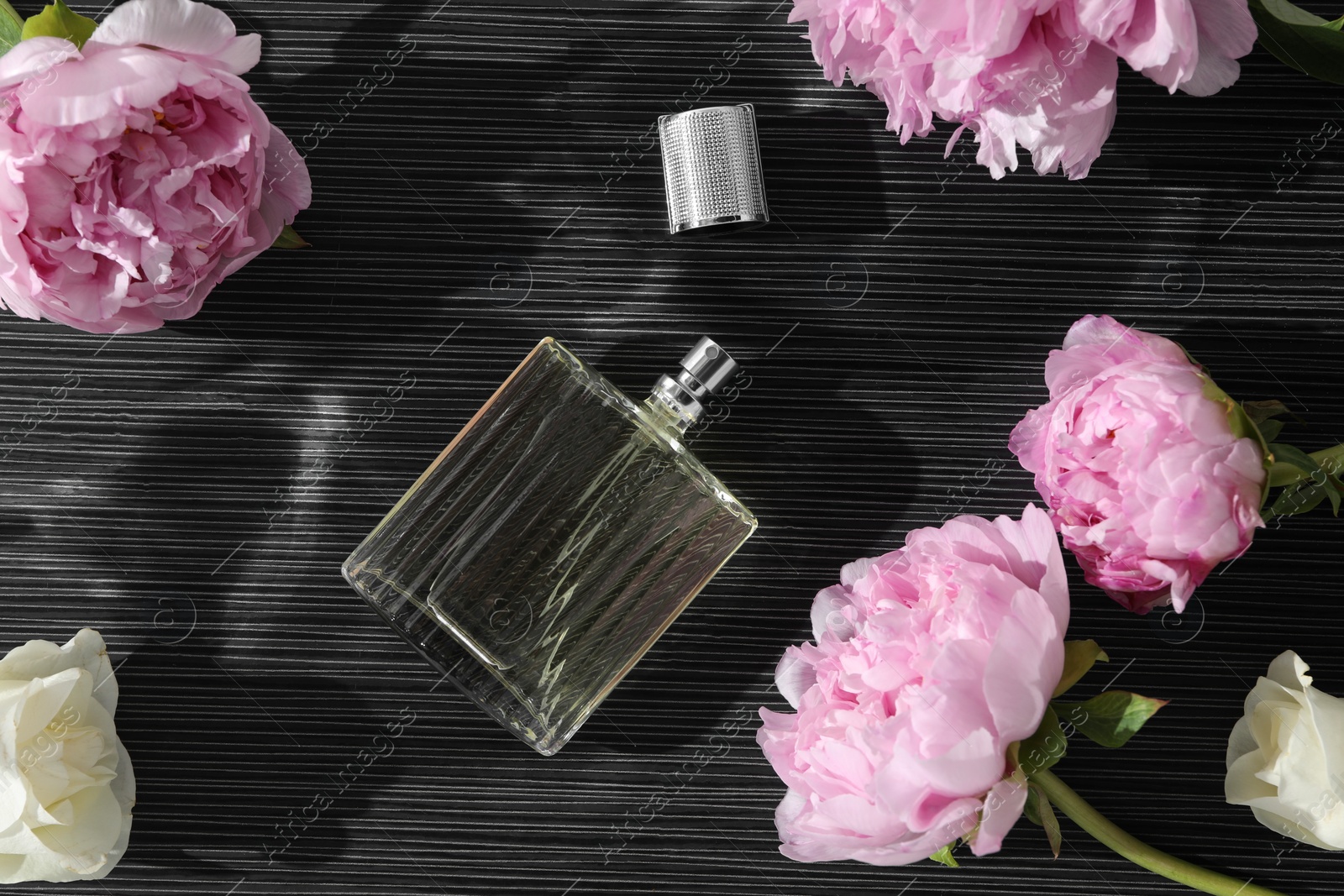 Photo of Luxury perfume and floral decor on dark background, flat lay