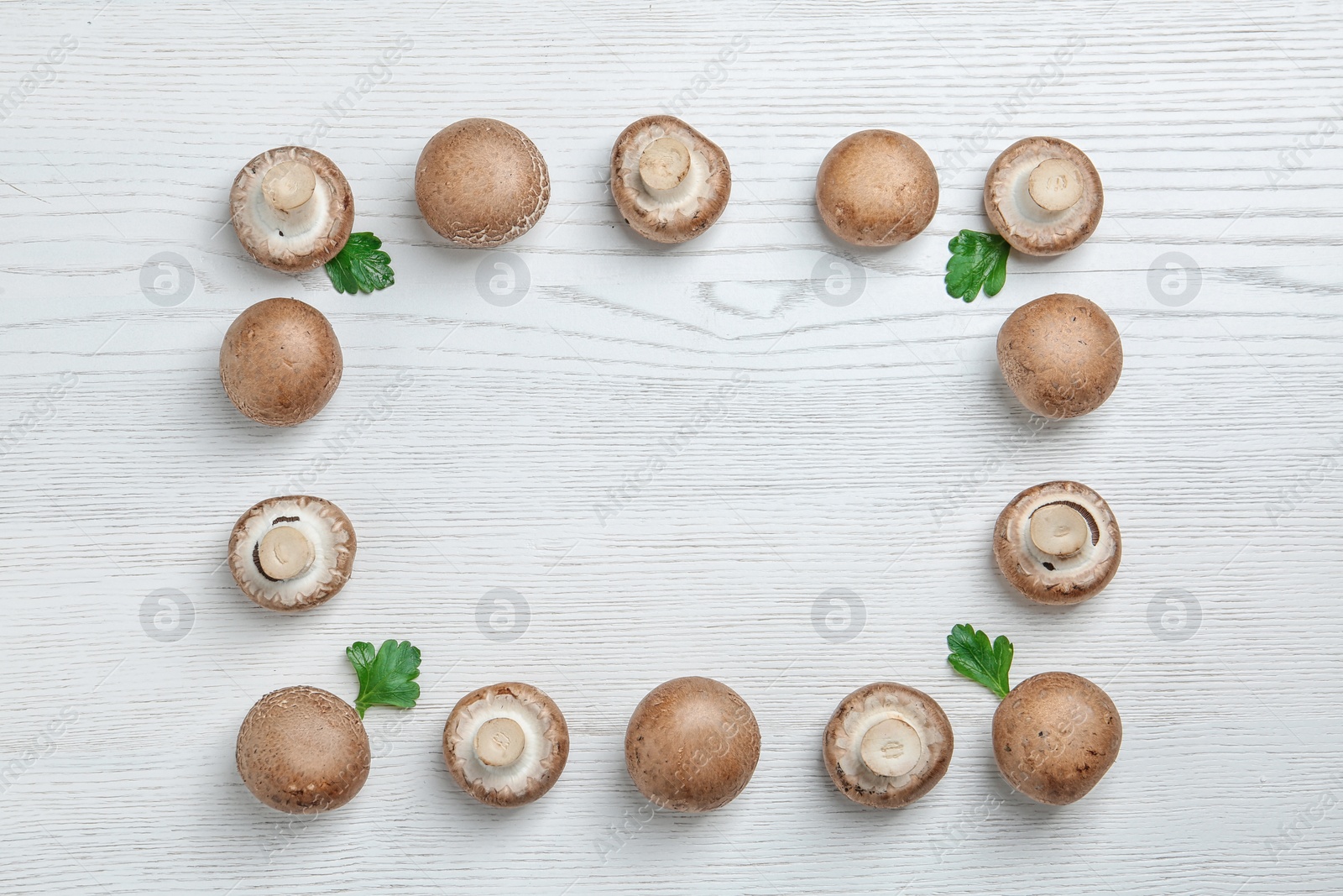 Photo of Frame made of fresh champignon mushrooms on wooden background, flat lay with space for text