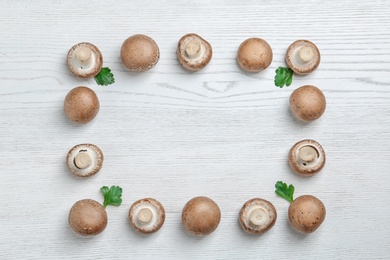 Photo of Frame made of fresh champignon mushrooms on wooden background, flat lay with space for text