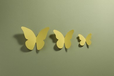Photo of Yellow paper butterflies on pale green background, top view