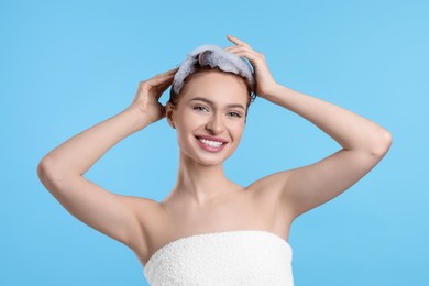 Photo of Happy young woman washing her hair with shampoo on light blue background