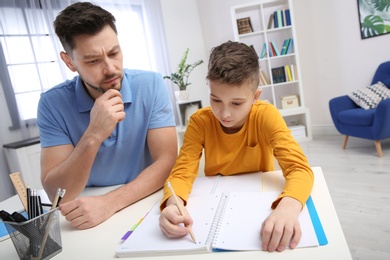 Photo of Dad helping his son with homework in room