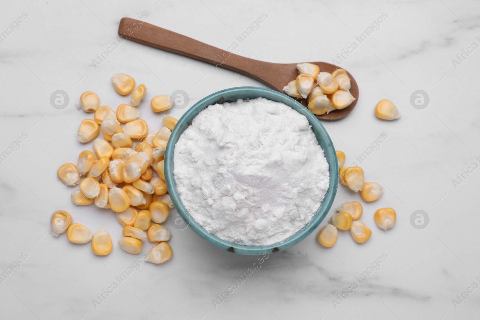Photo of Bowl with corn starch and kernels on white marble table, flat lay