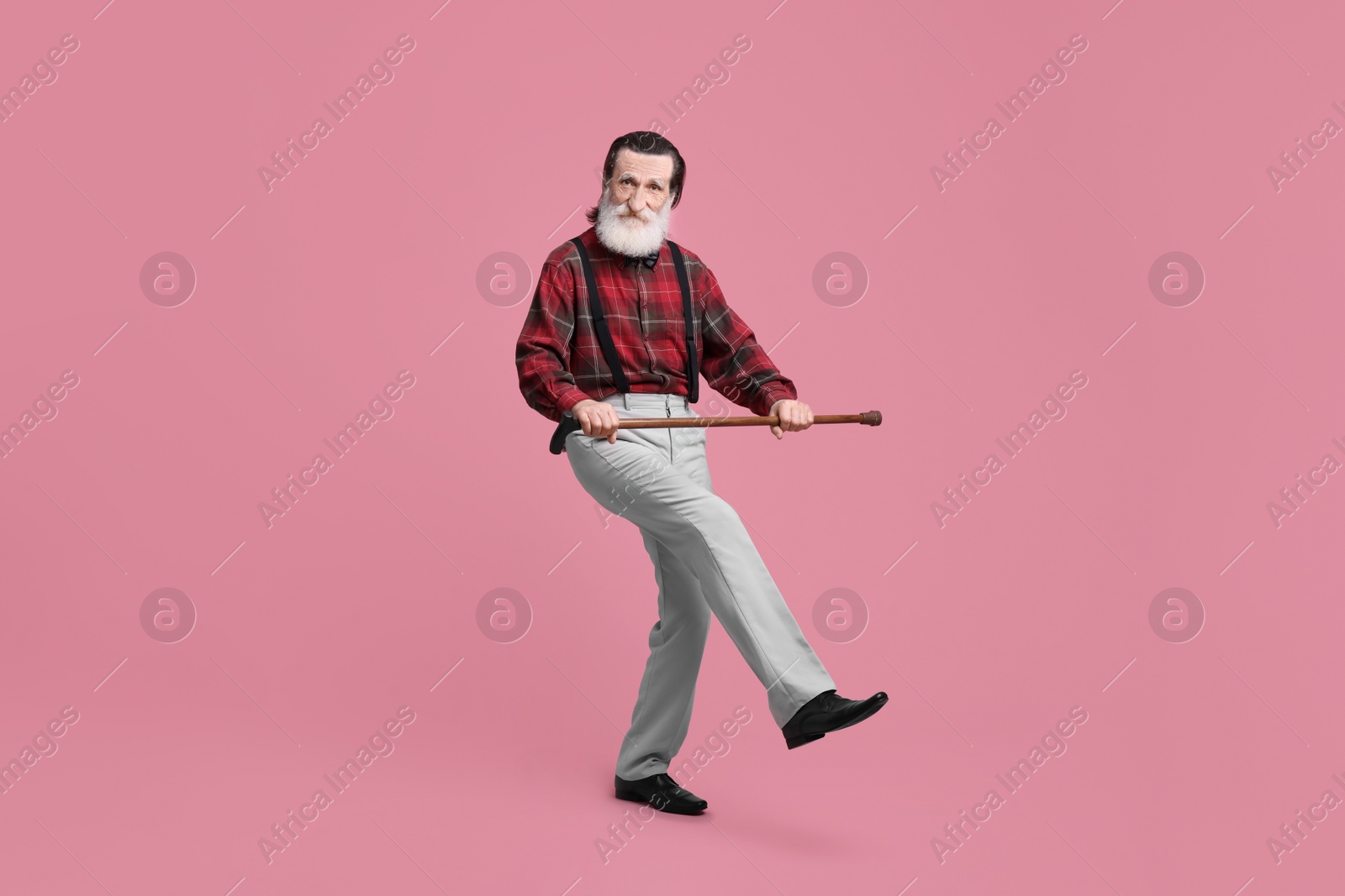 Photo of Senior man with walking cane on pink background