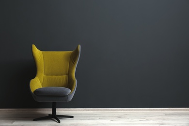 Photo of Comfortable office chair near black wall indoors. Space for text