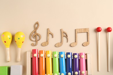 Photo of Baby song concept. Wooden notes, kids xylophone and toys on beige background, flat lay. Space for text