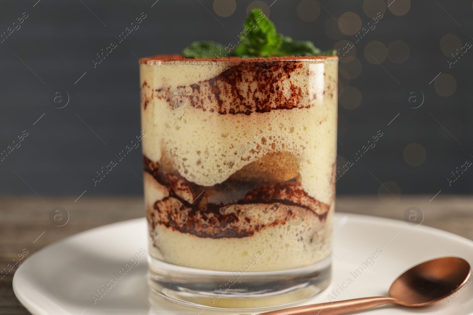 Photo of Tasty tiramisu and mint in glass on table, closeup