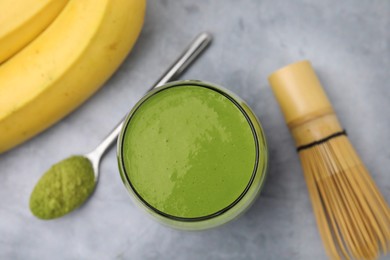 Photo of Glass of tasty matcha smoothie on light grey table, flat lay