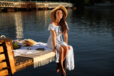 Photo of Young woman spending time on pier at picnic
